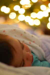 Sick baby Mattelyn asleep with her rosy chapped cheeks next to the Chrismas Tree.